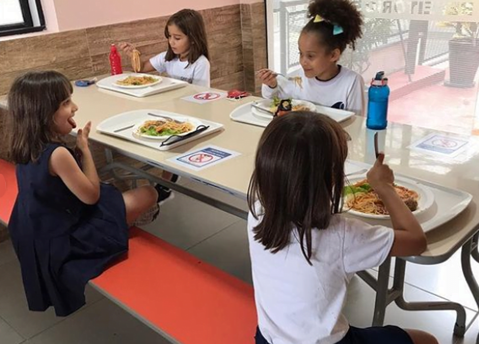 Crianças sentadas na mesa durante o almoço.